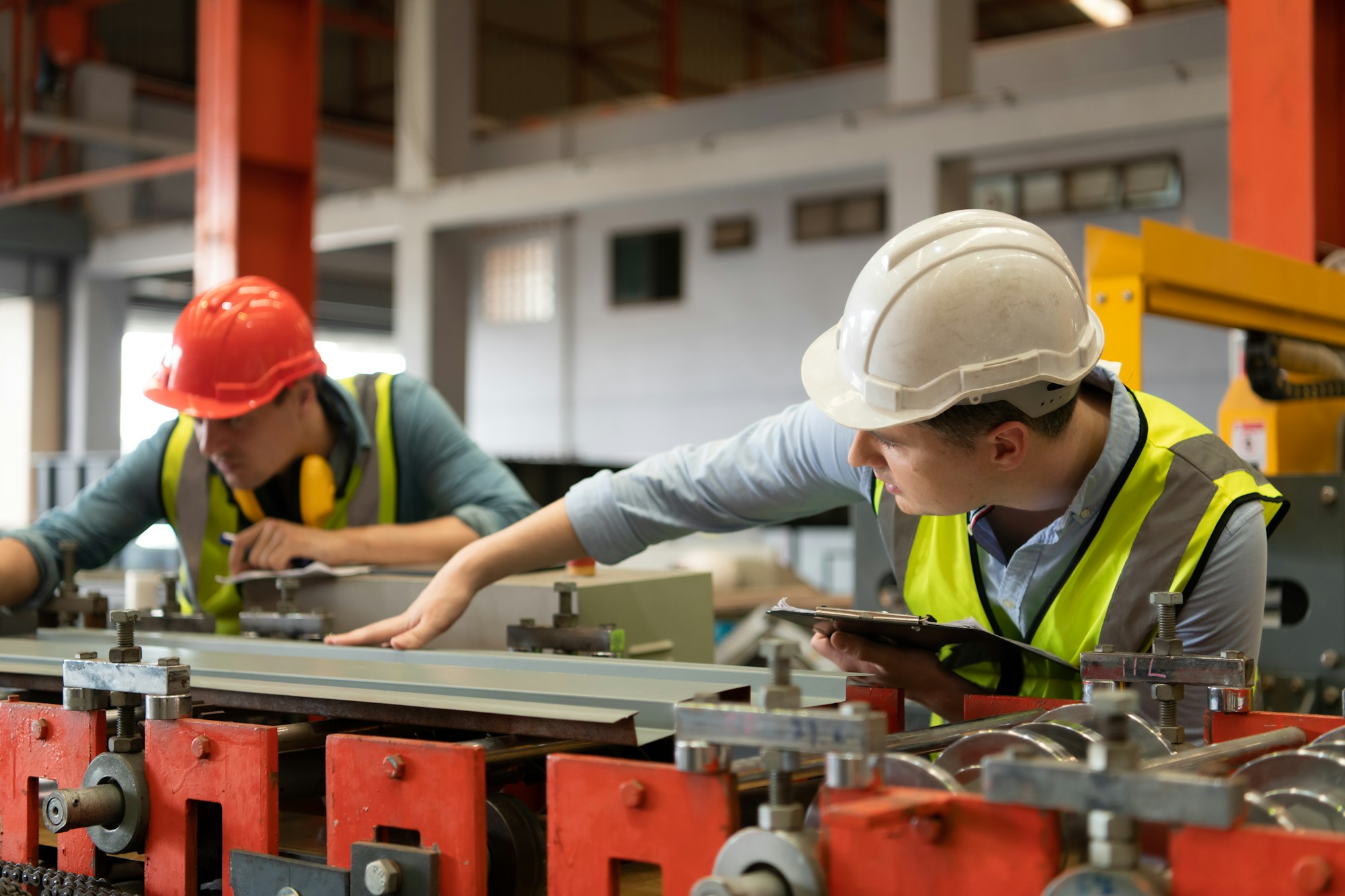 Two young engineers Testing and verifying the operation of the machines forming metal sheet tiles